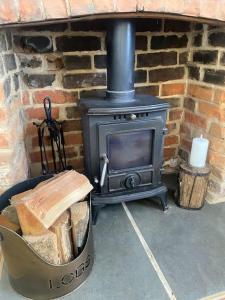 a black stove in a brick fireplace with a trash can at Cosy cottage in Chard