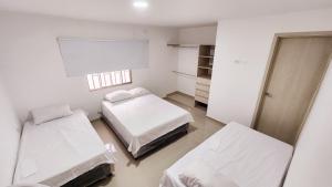 um quarto branco com 2 camas e uma janela em Casa Hotel Hefziba em Barranquilla