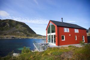 a red house on the shore of a body of water at Cabin in Lofoten with spectacular view in Ballstad