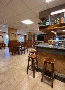 restauracja z drewnianymi stołami i stołami oraz bar w obiekcie Hostal El Corzo w mieście Villafranca