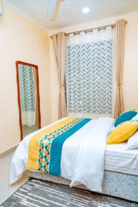 Schlafzimmer mit einem Bett und einem Spiegel in der Unterkunft F.A.M Homes Tabata in Daressalam