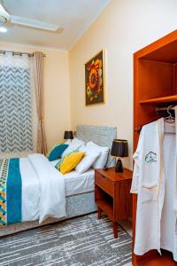 ein Schlafzimmer mit einem Bett und einem Tisch mit einer Lampe in der Unterkunft F.A.M Homes Tabata in Daressalam
