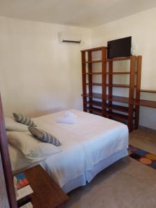 a bedroom with a white bed and a television at Pousada Vila do Beco in Arraial d'Ajuda