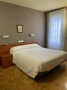 a bedroom with a large bed with a white comforter at Hostal El Corzo in Villafranca