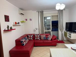 een woonkamer met een rode bank met patriottische kussens bij 3 Bedrooms Apartment in Shkodër