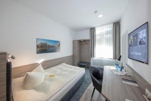 a bedroom with a bed and a desk with a computer at Hotel Reichshof garni in Schwerte