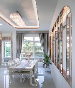 a dining room with a table and chairs and windows at Luxury Entire House short term rent In Buriram City for SongKran Festival in Buriram