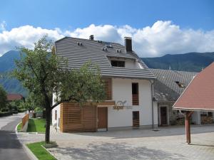 a white house with a gambrel roof on a street at Apartments Supermjau in Bovec