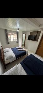 1 dormitorio con 2 camas y TV de pantalla plana en Casa Inteira com Churrasqueira, en Ponta Grossa