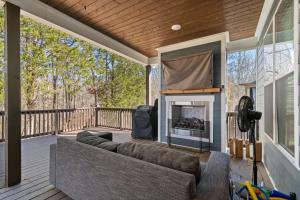 porche con sofá y chimenea en la terraza en Lakeside Cottage w/Golf Cart, Hot Tub, & Fire Pit, en Estill Springs