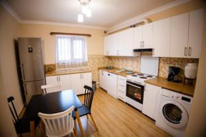 a kitchen with white cabinets and a table and a refrigerator at Stepsa Guest House in Lermontovo