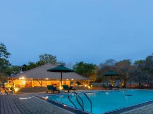 ein Pool mit Sonnenschirmen und Stühlen sowie ein Gebäude in der Unterkunft Joe's Bungalow Yala in Kirinda