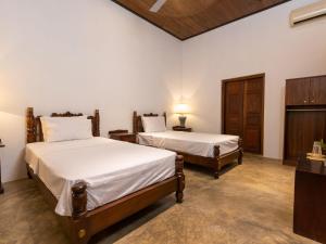 a bedroom with two beds and a table with a lamp at Joe's Bungalow Yala in Kirinda +25 photos