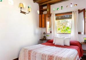 a bedroom with a bed with a red blanket and a window at La Casa del Hornero in Piriápolis