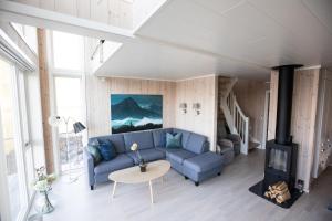 a living room with a blue couch and a fireplace at Cabin in Lofoten with spectacular view in Ballstad