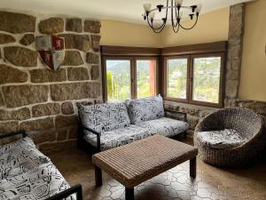 a living room with a couch and a stone wall at Picos Pardos CRA-AV-1088 in El Barraco