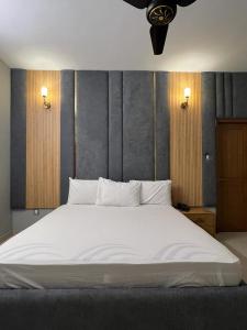 a bedroom with a large bed with white sheets at Marigold Accommodations in Karachi