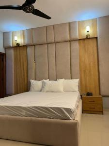 a bedroom with a large bed with a ceiling fan at Marigold Accommodations in Karachi