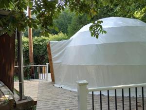 biały namiot siedzący na pokładzie pod drzewem w obiekcie GlampOut Resort - Elk River w mieście Sutton