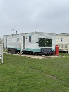 a mobile home parked in a yard with a bench at Ingoldmells -Caravan- Sleeps 6 - Seaside - Parking in Skegness
