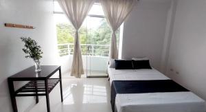 1 Schlafzimmer mit 2 Betten, einem Tisch und einem Fenster in der Unterkunft Hotel Loma Hermosa in Piura