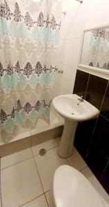 a bathroom with a sink and a toilet and a shower curtain at Hotel Loma Hermosa in Piura