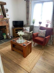 a living room with a vase of flowers on a coffee table at Cosy cottage in Chard +46 photos