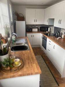 a kitchen with white cabinets and a wooden counter top at Cosy cottage in Chard