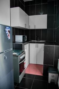 eine kleine Küche mit weißen Schränken und einem Kühlschrank in der Unterkunft CondoLind - Lomé 