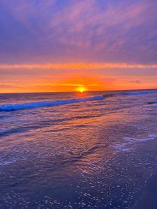a sunset on the beach with the ocean at Oceanside Getaway at Tuscan Village Condominiums in Oceanside +1 photo