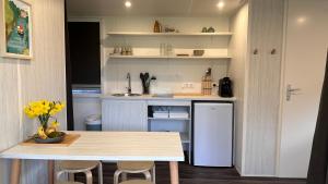 a kitchen with a table and a white refrigerator at Coco Sweet in Warmond