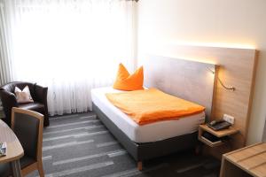Habitación de hotel con cama con manta naranja en Hotel - Restaurant BERGHOF en Berghausen