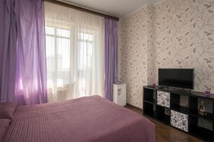 ノヴォシビルスクにあるApartments Freedom on Kirovaのベッドルーム1室(ベッド1台付)、紫色のカーテン付きの窓が備わります。