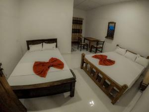 two beds in a room with towels on them at Sinharaja Forest Lodge in Deniyaya