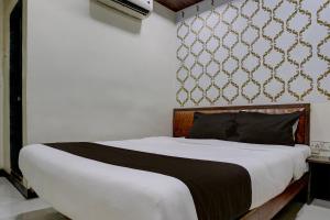 a bedroom with a large bed with white sheets and a wall at Mumbai Residency in Mumbai