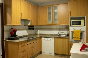 a kitchen with wooden cabinets and white appliances at Maison Camelias en Pontevedra centro con parking incluído in Pontevedra