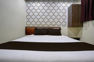 a bedroom with a white bed with a black pillow at Mumbai Residency in Mumbai