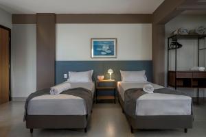 a room with two beds and a table with a lamp at Lym Flat Hotel in Uberlândia
