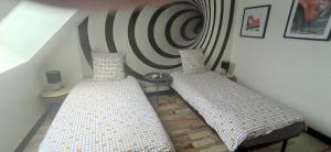 2 camas en una habitación con una pared a rayas en Au bonheur du logis, en Fougères
