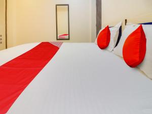 Bett mit roten und weißen Kissen in einem Zimmer in der Unterkunft Super OYO Flagship Hotel Space Inn in Nagpur