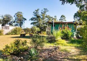 Un jardín con una casa verde al fondo. en La Casa del Hornero, en Piriápolis