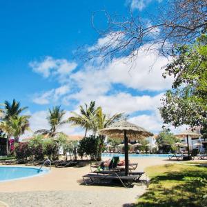 a beach with chairs and umbrellas and a swimming pool at Coastal Comfort at Tortuga Beach - 292 in Prainha