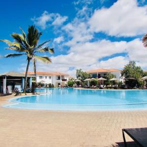 a large swimming pool with a palm tree and buildings at Coastal Comfort at Tortuga Beach - 292 in Prainha