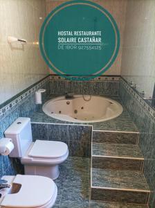 y baño con aseo y bañera. en Hostal Restaurante Solaire, en Castañar de Ibor