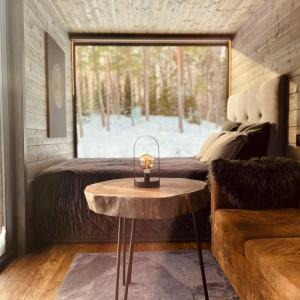 a bedroom with a bed and a table in front of a window at Reborn Cabins in Pabaži