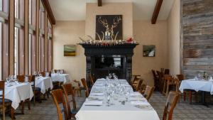 comedor con mesas y sillas blancas y chimenea en Hôtel et Centre de Villégiature Lac Carling en Grenville-sur-la-Rouge