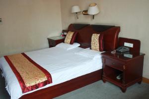 1 dormitorio con 1 cama y mesita de noche con teléfono en Taizhou Taishan Business Hotel, en Taizhou