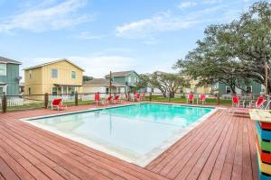 a swimming pool with red chairs on a wooden deck at The Yellow Getaway - Community Pool in Rockport