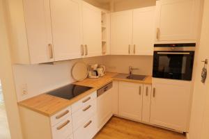 a white kitchen with white cabinets and a sink at OstseeBrise - Sünnenkieker WE5 - ABC348 in Beckerwitz