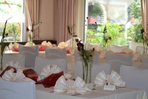 ein Zimmer mit weißen Tischen und Stühlen mit Blumen darauf in der Unterkunft Hotel & Restaurant Zur Linde in Freital